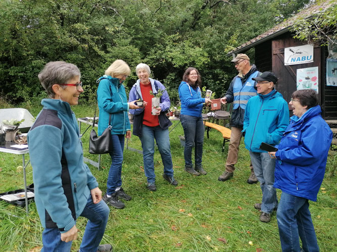 Eine Gruppe Personen, einige halten Pflanzen in der Hand.