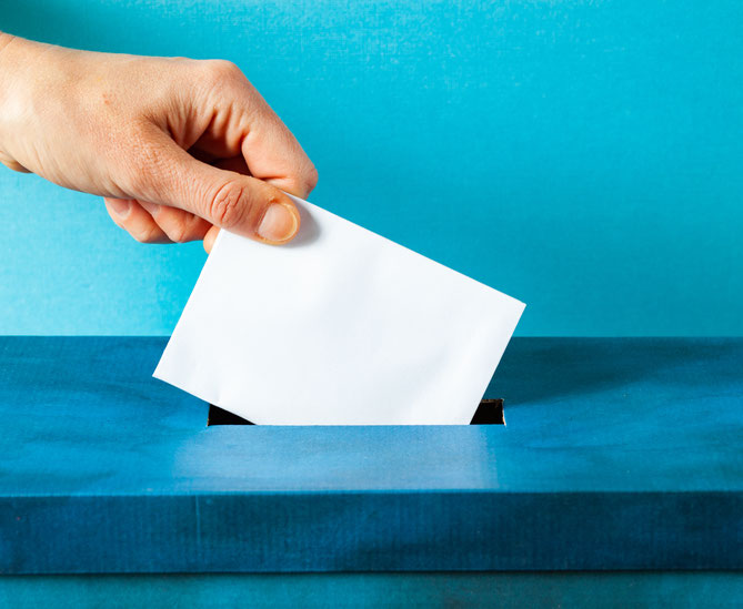 Hand putting ballot paper into ballot box