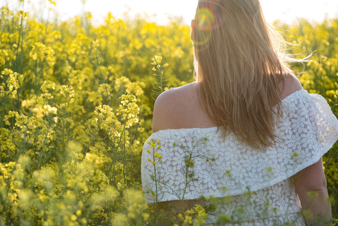 Bild von einer Frau die auf eine Blumenwiese schaut