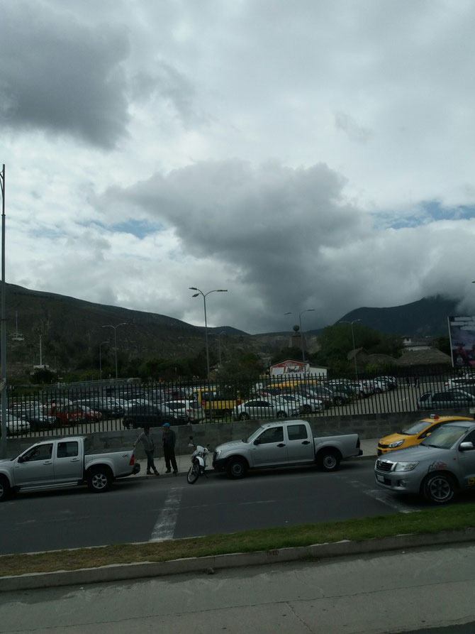 Mitad del Mundo, die "Mitte der Welt" vom Bus aus. Das steinerne Monument ist hinter dem Parkplatz zu sehen. 
