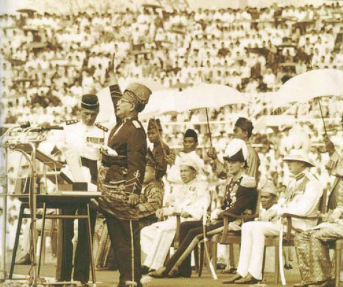 LE PREMIER MINISTRE TUANKU ABDUL RAHMAN (1903 + 1990) CRIE 7 FOIS "PERMEKA"  - LIBERTE ou INDEPENDANCE - REPRIS EN CHOEUR PAR LE STADE ARCHI-COMBLE  . ENSUITE RETENTIT L'HYMNE NATIONAL  "NEGARAKU"