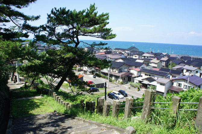 海と山に囲まれながら、互いに肩を寄せ合う名立の街並み。子どもの頃、冬になると、手前の神社の階段でスキー遊びをしていました