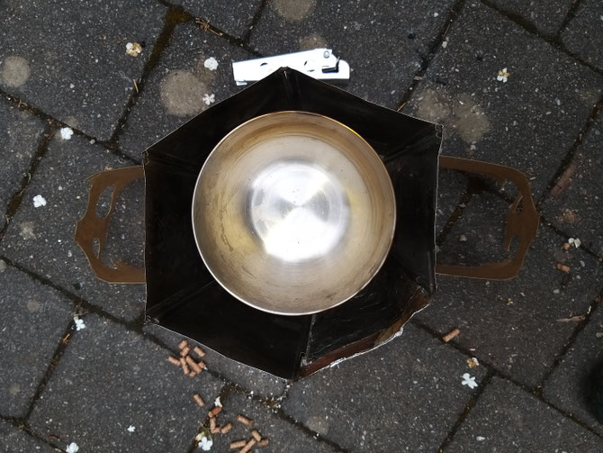 The Permastove V4 with ss bowl, hexagonal heat shield resting on half sections of cardboard from a used 6 pack of beer