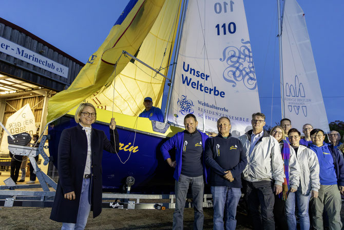 Landtagspräsidentin Birgit Hesse (li.) überreicht ein Spinnaker an die Schwerin-Crew des Schweriner Marineclubs. Foto: SMC/Stephan Rudolph-Kramer