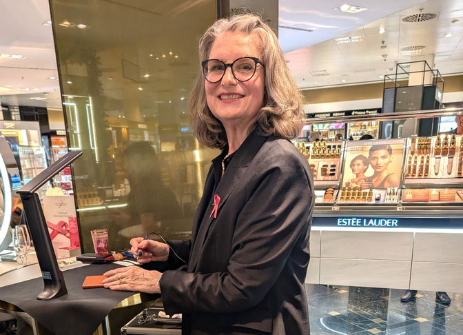 Sigrid Bengel in Aktion: Exklusive Handprägung für Tom Ford im Breuninger Stuttgart. Die Künstlerin im schwarzen Blazer mit rosa Schleife graviert personalisierte Leder-Accessoires an einer professionellen Station. Im Hintergrund der luxuriöse Verkaufsber