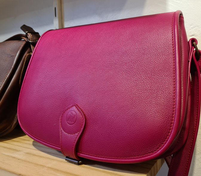 Une belle besace en cuir de veau couleur framboise grainé.