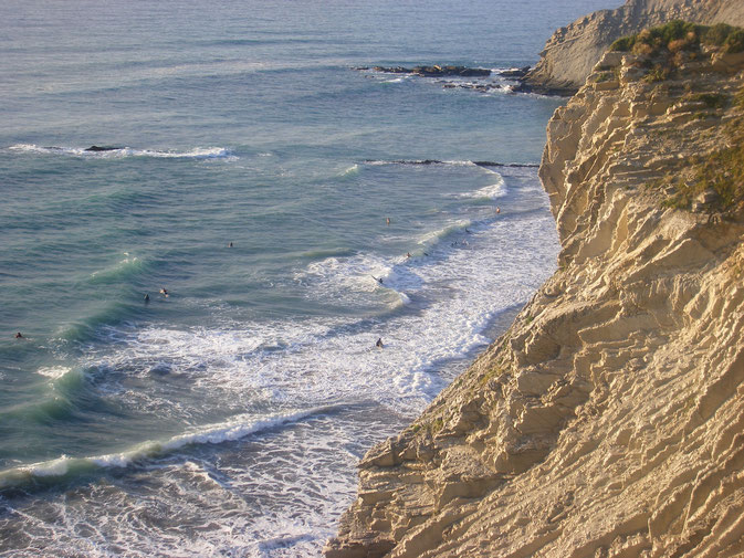 Vista de la playa con surfistas disfrutando de las olas.