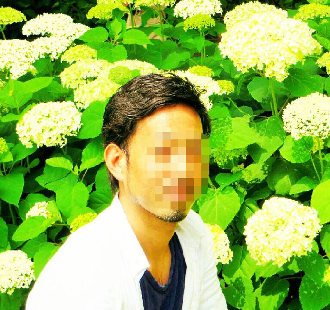 大阪梅田のメンズリラクゼーションサロン「forest hands」オーナーセラピスト徹平のプロフィール写真。白いあじさいと鮮やかな緑の葉を背景にした、白いシャツを着た爽やかな姿。