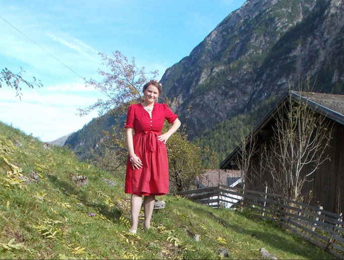 Sängerin Silke Scharf in einem wunderschönen roten Dirndlkleid in den Tiroler Bergen in Österreich 