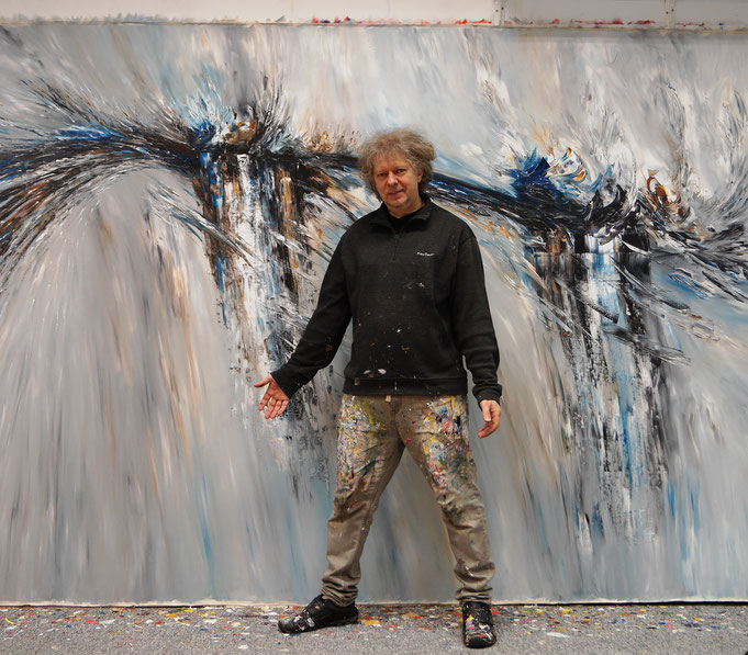 Peter Nottrott vor seinem Gemälde im Atelier, was die 500 x 200 cm veranschaulicht.