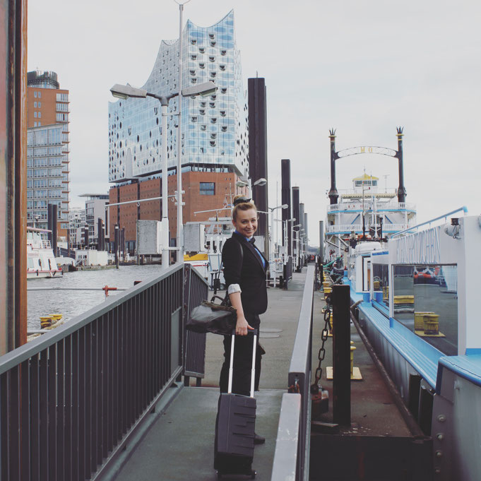 Constanze Marienfeld lächelt auf dem Weg zu einer Trauung, im Hintergrund erkennt man die Elbphilharmonie