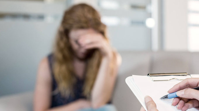 Junge Frau stützt den Kopf in die Hand – unscharfes Symbolbild für depressive Verstimmung oder Depression.