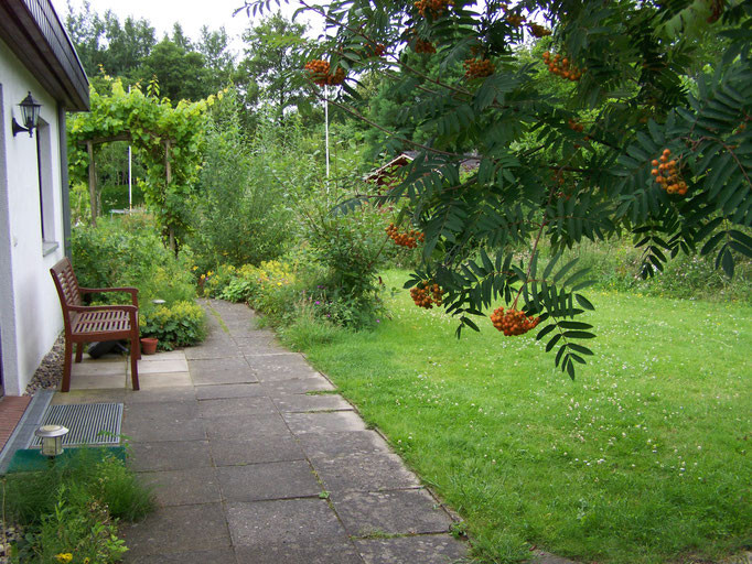 Eingang zur Ferienwohnung mit Sitzbank davor und grünem Rasen im Sommer
