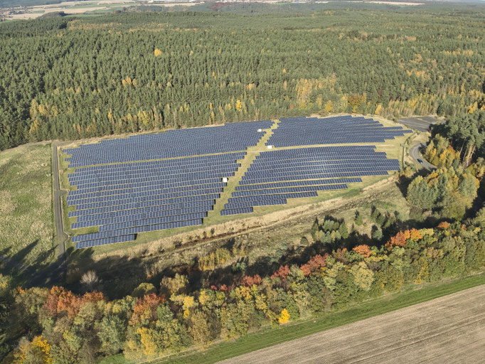Luftaufnahme eines Solarparks mit großflächigen Photovoltaik-Modulfeldern zur Vorbereitung einer thermografischen Drohneninspektion. 
