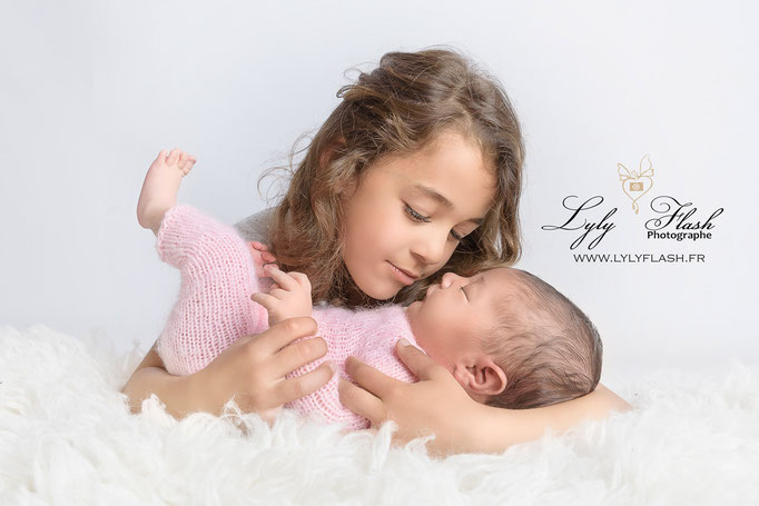photo de naissance du nouveau-né sa sœur observe sa petite sœur pour une photo tout en tendresse par lyly flash photographe près de Saint Maximin la sainte baume