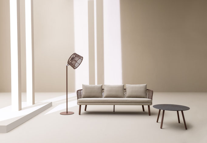 Divano da esterno minimal con tavolino e lampada decorativa in ambiente chiaro e raffinato.