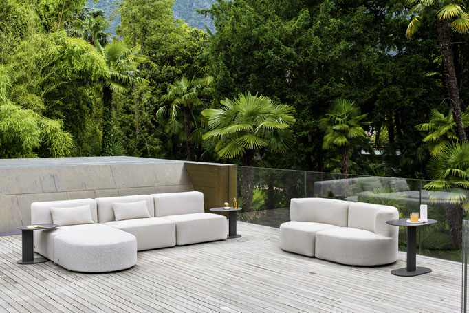 Divano e poltrone outdoor su terrazza immersa nel verde con tavolino laterale.