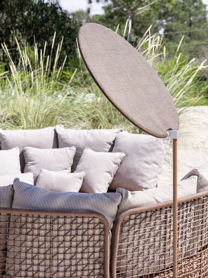 Divano da esterno con cuscini rosa e struttura intrecciata, dettaglio di seduta lounge outdoor.