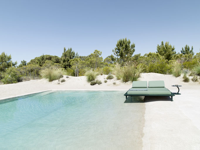 Lettino prendisole verde a bordo piscina, arredo outdoor per zona relax in ambiente naturale.