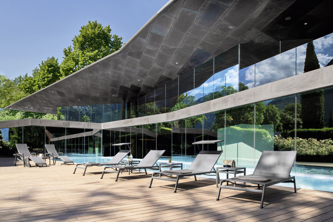 Lettini e sedute outdoor su terrazza con piscina, materiali resistenti e design contemporaneo