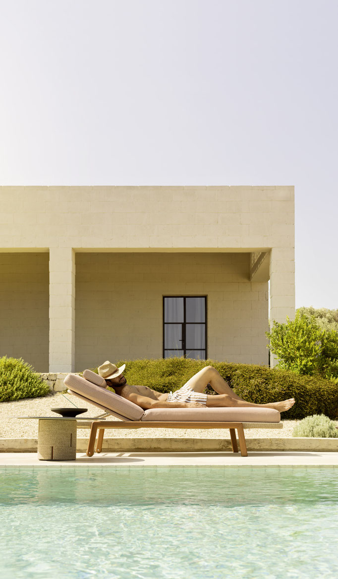 Lettino prendisole con cuscino rosa a bordo piscina, arredo outdoor per relax all’aperto.