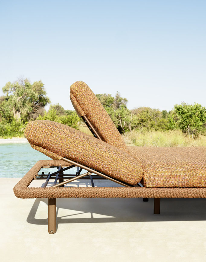 Lettino prendisole outdoor con cuscino arancione e struttura regolabile vicino piscina.