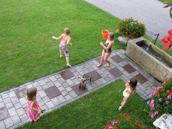 Die Gästekinder spielen mit Wasser im Garten