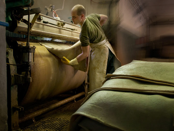 Die Häute werden kurz in warmes Wasser gelegt und danach auf der Glättmaschine (Streichmaschine / Schlickerwalze) narbenseitig restgesäubert. Der Gerber spricht hier von der Entfernung des „Gneist“, der aus Schmutzteilen besteht.