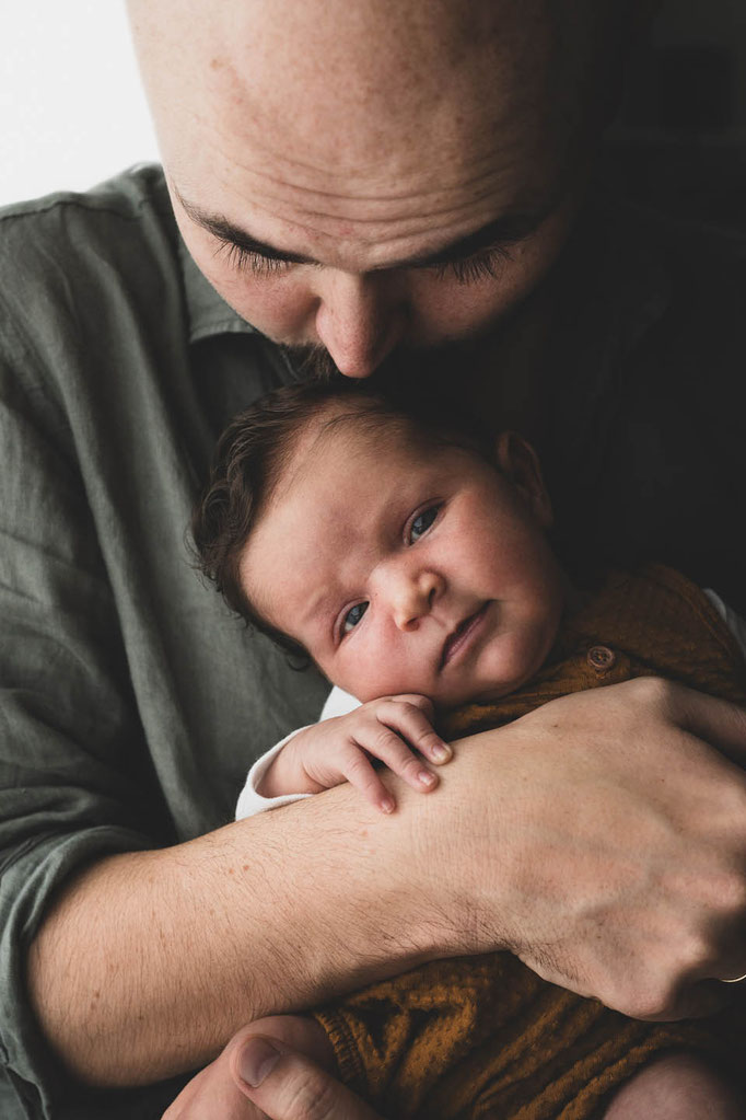 baby in papas arm, blick in die kamera. Daddy kiss