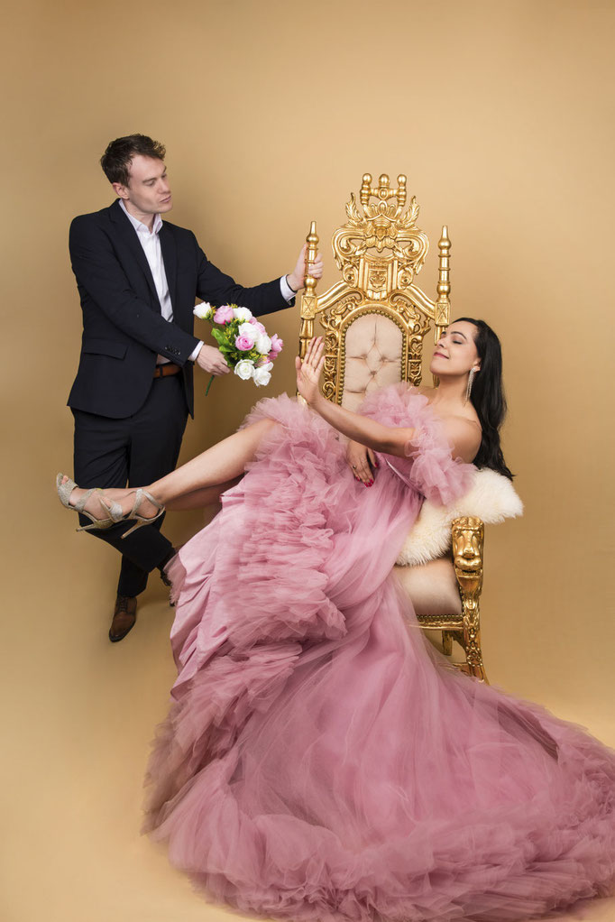 Grappig shot van een stel met vrouw op troon met gouden achtergrond