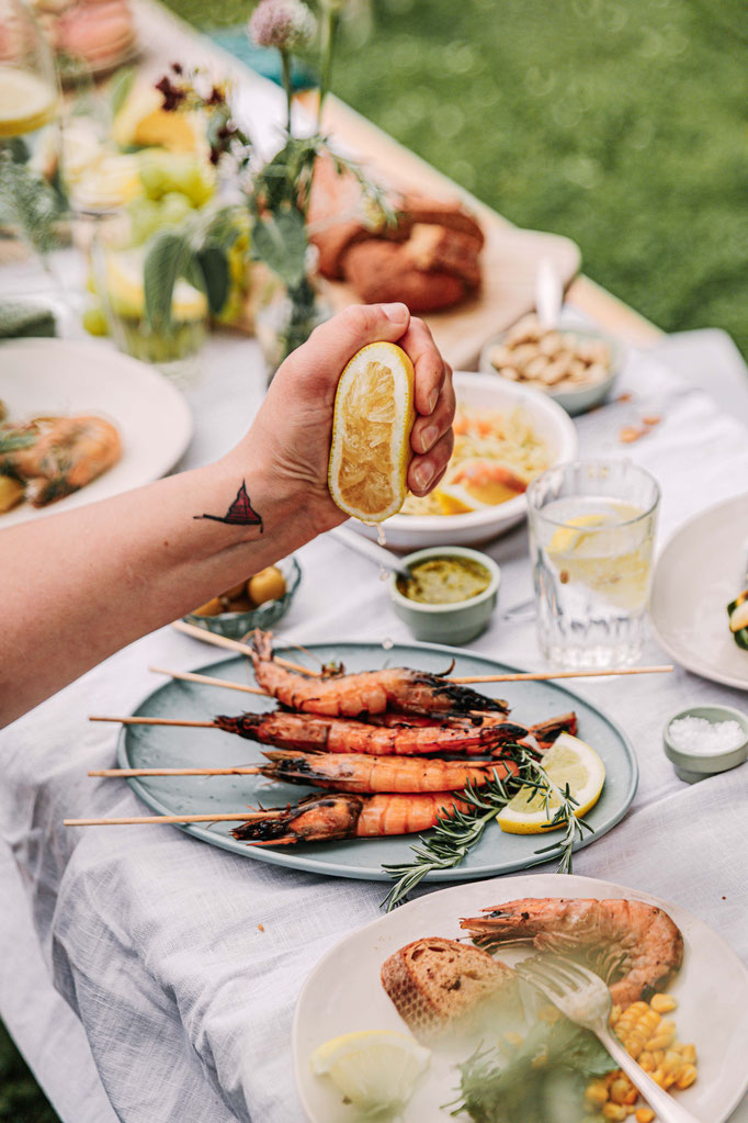 Nachhaltig gezüchtete Garnelen von Gamba Zamba bei sommerlichem BBQ-Tisch im Grünen – frisch serviert mit Zitrone und regionalen Beilagen aus Hannover