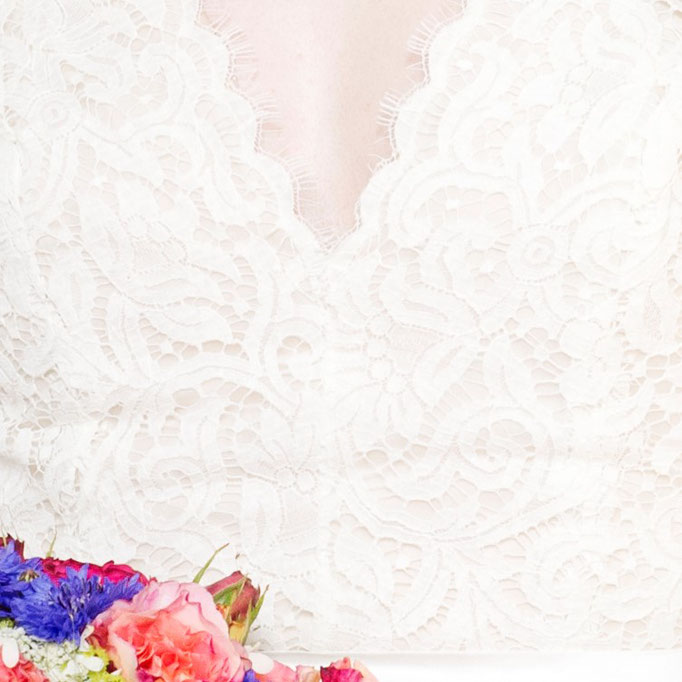 Brautkleid von Luisa Oberteil Spitze mit tiefem V-Ausschnitt vorne und hinten Faltenrock aus Dupionseide Detailaufnahme Spitze