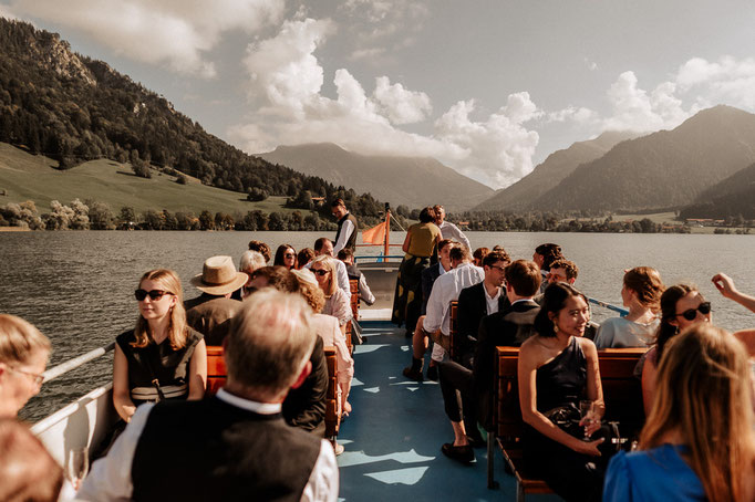 Schliersee Schifffahrt auf dem Deck mit Hochzeitsgästen und Brautpaar. Traumhafte Aussicht auf die Berge. Hochzeitsfotograf Schliersee.