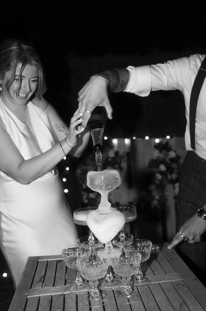 Braut und Bräutigam schenken einen Champagnerturm ein