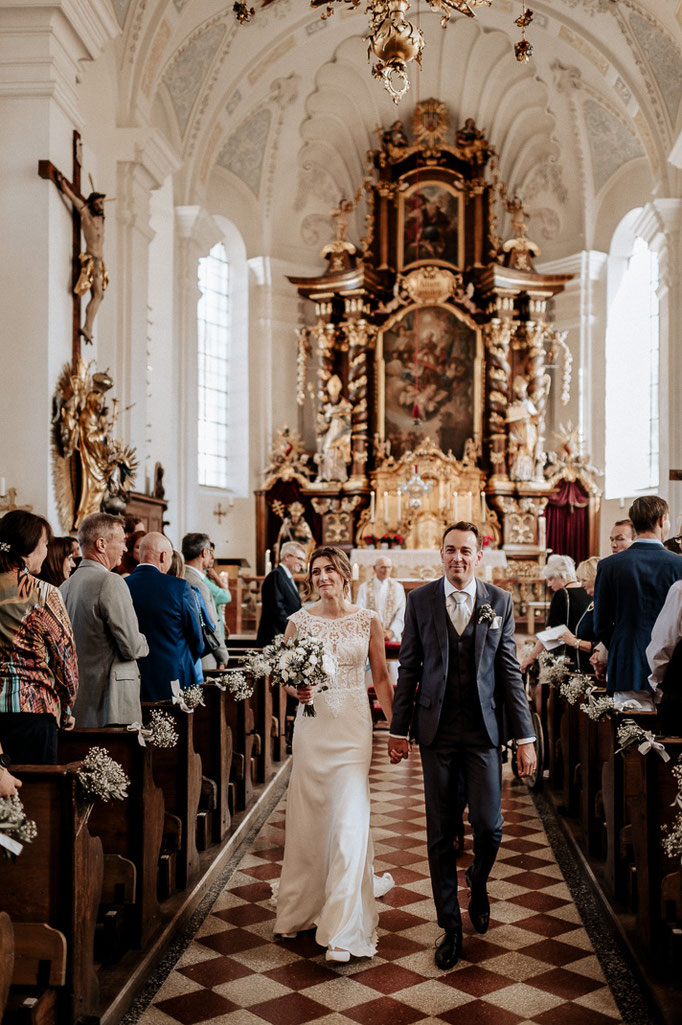Hochzeitsfotograf am Schliersee. Das Brautpaar zieht gemeinsam aus der Kirche aus. Reportagefoto  am Schliersee.