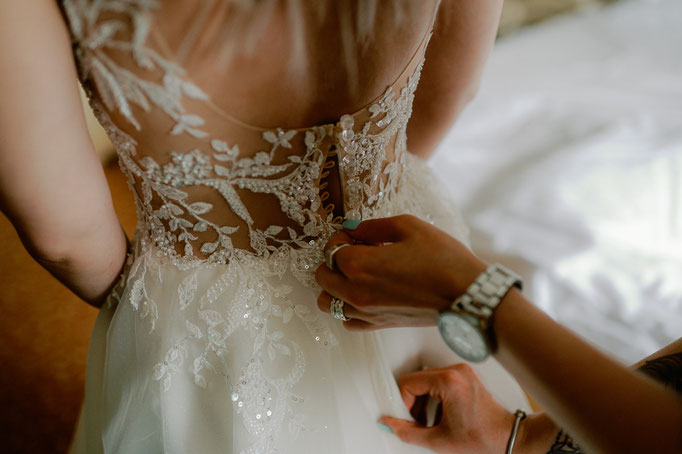 Brautkleid wird beim Getting Ready am Rücken zugeknöpft