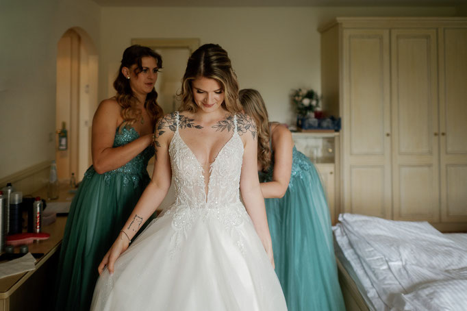 Braut im Kleid beim Getting Ready mit ihren Begleiterinnen