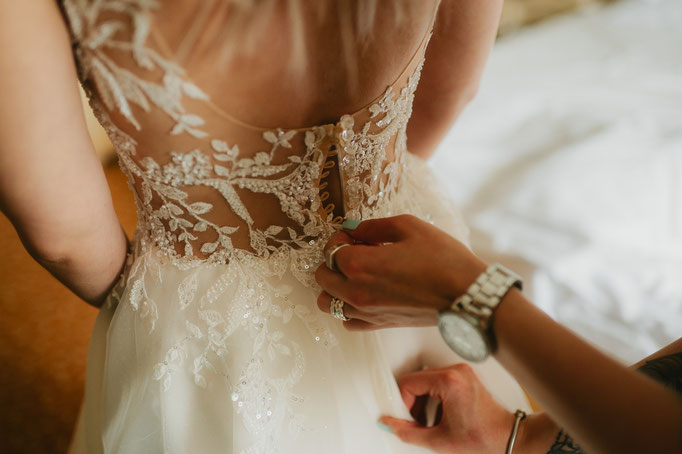 Brautkleid wird beim Getting Ready am Rücken zugeknöpft