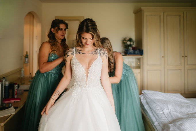 Braut im Kleid beim Getting Ready mit ihren Begleiterinnen