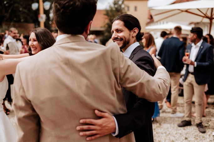 Ein Freund sieht zum Bräutigam während er den Arm um ihn legt