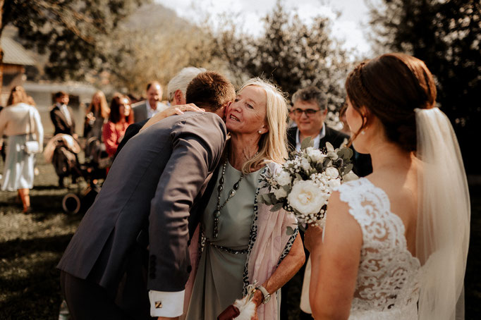 Hochzeitsfotografenpaar Andreas Reiter und Manuela Reiter am Schliersee. Ein Hochzeitsgast gratuliert dem Bräutigam und umarmt ihn.