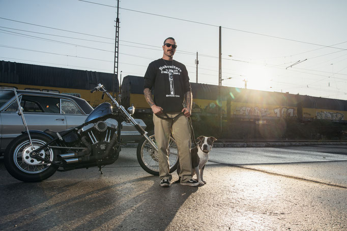 Mann bei Gegenlicht mit Harley Davidson Chopper, Oldtimer und Hund.