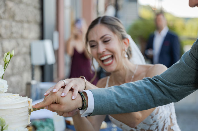 Glückliche Braut beim Anschnitt der Hochzeitstorte mit ihrem Bräutigam