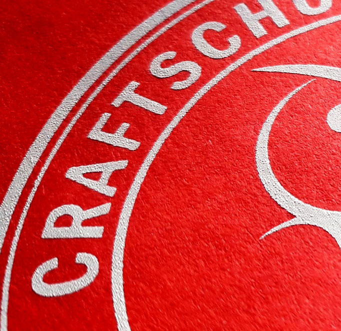 Teil eines Logos in Weiß auf Rot drucken im "Einzelworkshop Siebdruck" Nähe Oldenburg und Bremen.