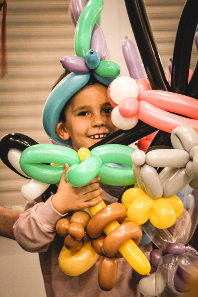 Kind mit bunten Ballonfiguren nach einer Ballonmodellage auf einem Kindergeburtstag
