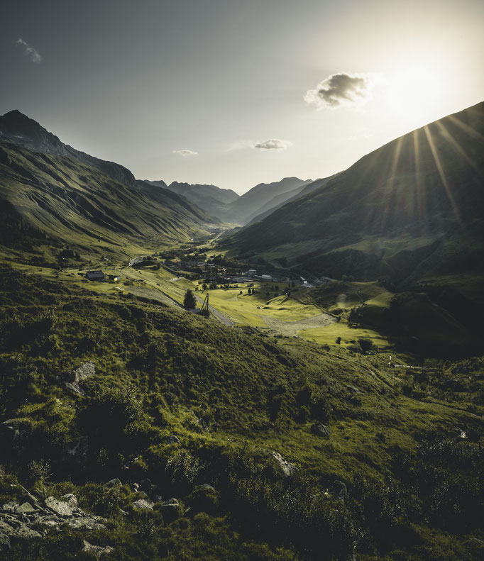 Fotografie von Andermatt von Bergen umgeben an schönen Sommertag