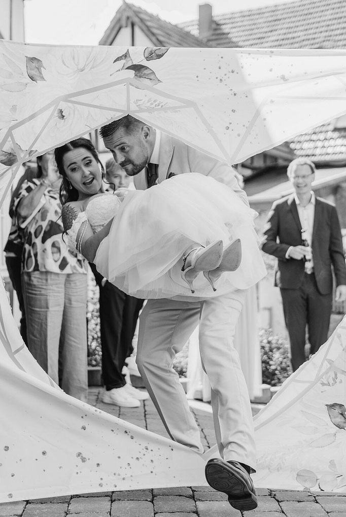 Herz ausschneiden und Bräutigam trägt Braut durch - Hochzeitsfotograf Bielefeld