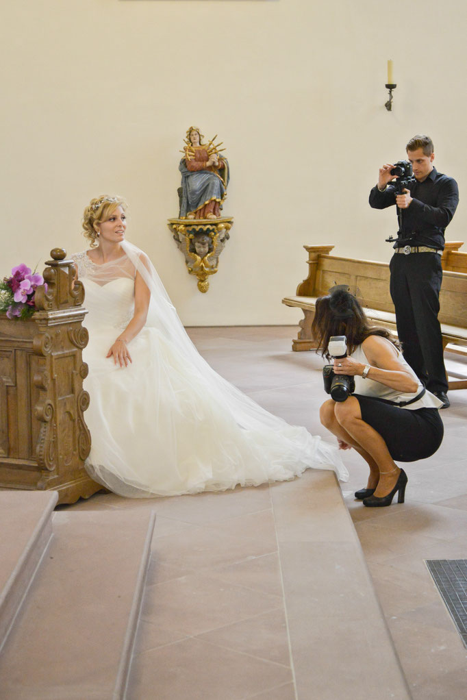 Hochzeitsreportage in der Kirche - die Hochzeitsfotografin richtet der Braut ihr Kleid - Hochzeitsfotrograf Bad Driburg