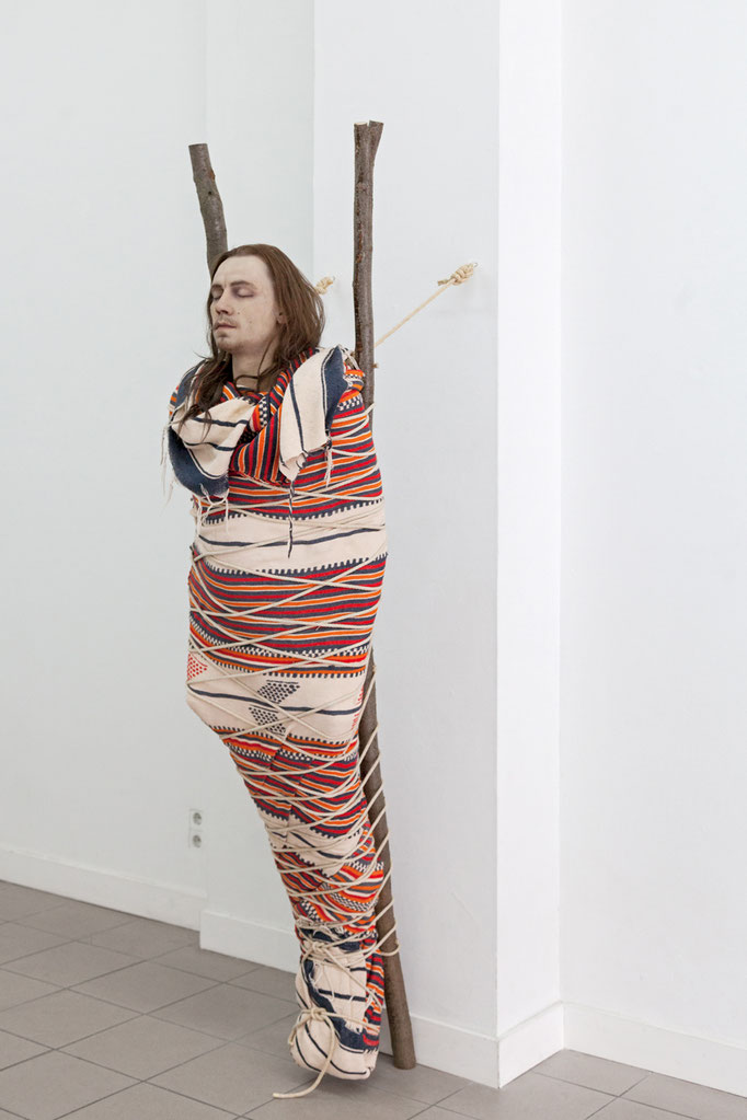 Manuel Frolik · Toter Indianer, 2017 Silikonkautschuk, Echthaar, Textilien, Seil, Holz, ca. 216 x 48 x 70 cm