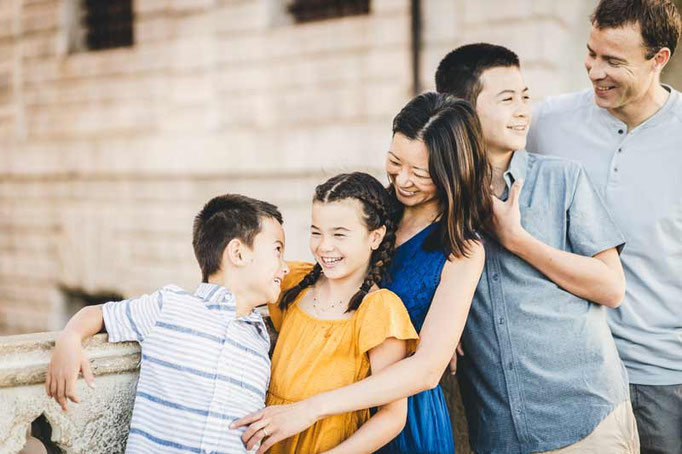 Professional Venice family photographer taking a low-angle shot of kids exploring a historic Venetian archway, focusing on playful interaction.